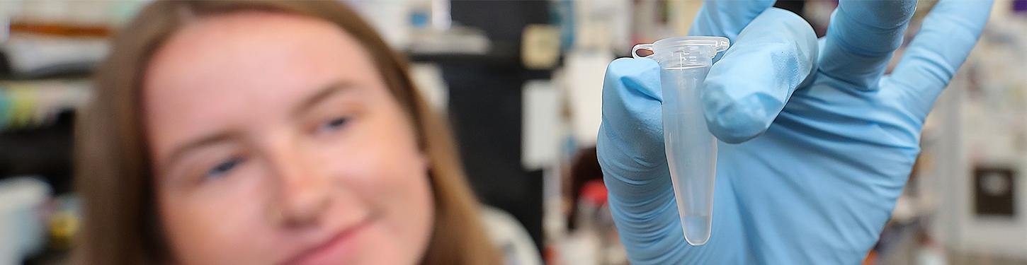 A student holds a vial in a gloved hand